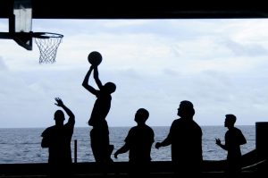 Silhouette of a basketball game played by the ocean, creating a striking visual scene.